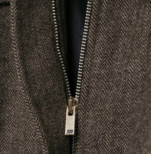 Close-up of herringbone fabric texture and silver metal zipper on bomber jacket