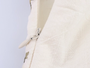 Close-up of the high-quality invisible zipper and green embroidery on the white dress