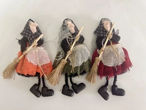 Detailed view of handmade fabric witch dolls in orange, green and red with brooms