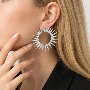 Glamorous oversized sunburst hoop earrings with sparkling rhinestones worn by a model