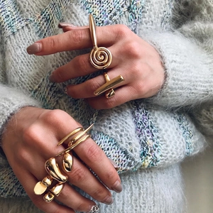 Close-up of stacked chunky gold geometric open rings on a model with knit sweater background