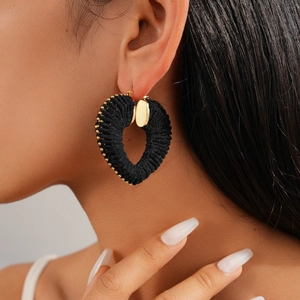Detail of woven heart hoop earrings with golden beads on a female model