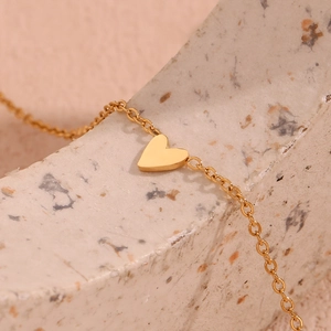 Macro detail of 18K gold plated heart pendant on minimalist stainless steel chain