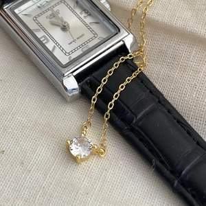 Detailed macro of a gold necklace with round zircon pendant over a Casio watch prop