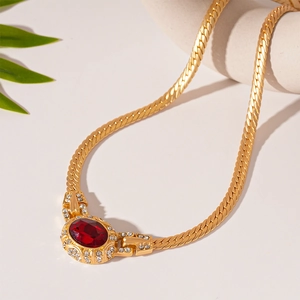 Close-up of vintage gold snake chain featuring an oval red gemstone and zircon accents