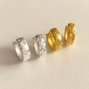 Macro detail of gold and silver hoop earrings with zircon and engraved celestial stars