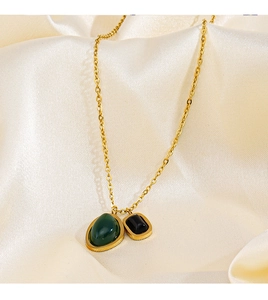 Détail du collier plaqué or 18K avec gemmes vertes et noires sur fond en soie beige