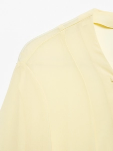 Close-up of the delicate shoulder stitching and soft fabric texture on the yellow shirt