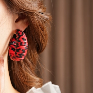 Macro detail of red and black leopard print C-shaped earrings worn by a model
