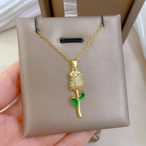 Detailed shot of gold rose pendant with green and clear crystals on a jewelry pad
