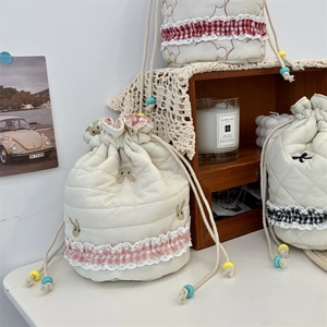 Detail of quilted drawstring pouches featuring rabbit embroidery and elegant lace trim