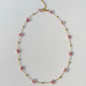 Detail of gold chain necklace with delicate pink and white floral beaded charms and clasp