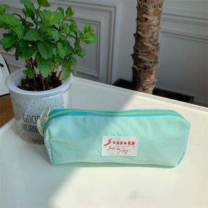 Close-up of mint green nylon multifunctional pencil case with SOZAKKA brand woven label