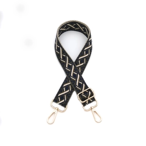 Détail d'une bandoulière tissée avec motif géométrique vert et crochets dorés