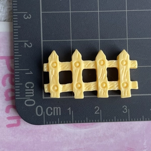 Macro view of a 3.5cm yellow resin fence miniature with wood texture on a ruler