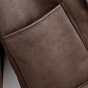 Détail de la veste en daim marron montrant la couture de poche et la texture