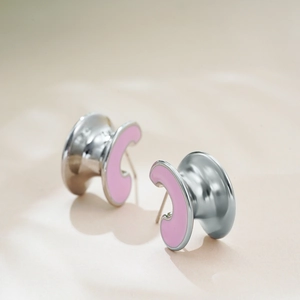 Detailed close-up of C-shaped stainless steel earrings with pink enamel inlay