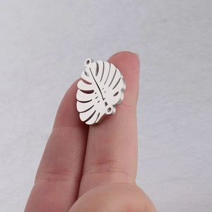 Close-up of a silver hollow palm leaf pendant made of mirror polished stainless steel