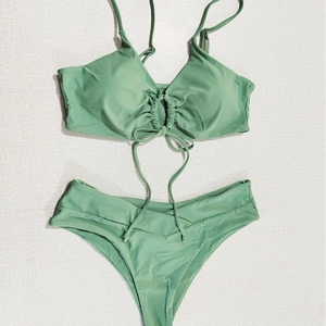Flat lay of sage green halter bikini set with ruched bow detail and high cut bottoms