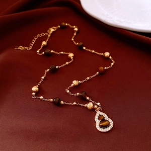 Tiger eye beads and gold gourd pendant necklace on elegant dark red silk background