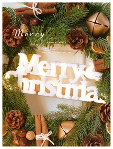 Close-up of glowing Merry Christmas LED light with pine cones and cinnamon sticks