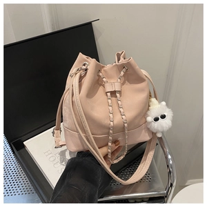 Pink bucket bag with chain strap and cute plush charm displayed on a metal shelf