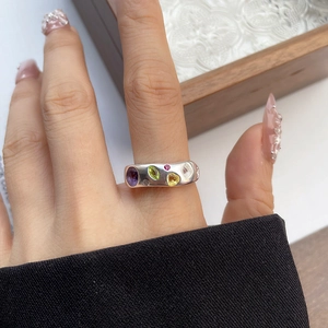 Detail of 925 silver ring with five colorful inlaid gemstones on a model hand