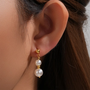 Detail of s925 silver pearl drop earrings with double pearls and gold accents