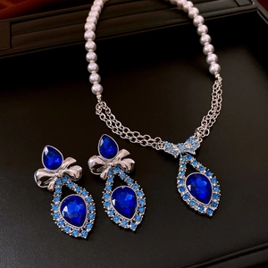 Blue teardrop crystal necklace and earrings set displayed on a premium black leather stand