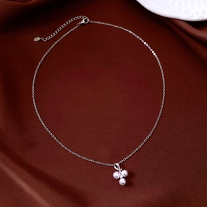 Detail of zircon pearl pendant necklace with lobster clasp on silk fabric background