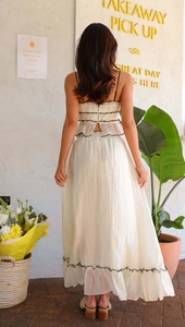 Detail view of white two-piece set featuring black wavy embroidery and pleated texture