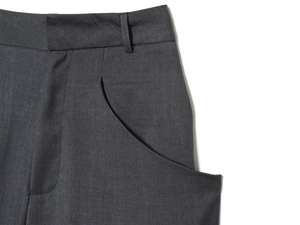 Detail of dark grey wool pants showing waistband loops and diagonal side pockets