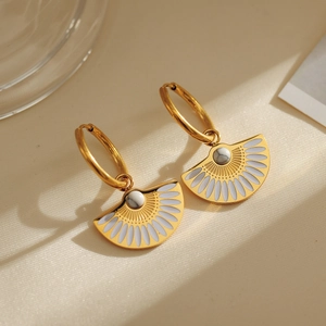 Détail de boucles d'oreilles éventail plaqué or 18k avec émail blanc et pierre marbre