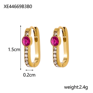 Detail view of gold U-shaped earrings with red zircon and white stones showing 1.5cm size