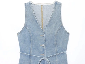 Détail du gilet en jean bleu clair avec col en V, boutons en métal et ceinture