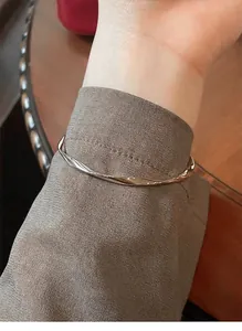 Elegant Mobius twist bangle in polished silver-tone finish on a person's wrist