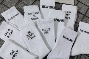 Close-up of white mid-calf socks with rib-knit texture and black street-style lettering
