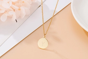 Détail d'un pendentif rond doré avec lettre Y gravée sur une chaîne de collier délicate