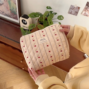 Macro detail of quilted cotton floral cosmetic bag with red embroidery and fabric label
