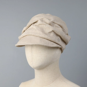 Linen newsboy cap in beige with natural pleats and silver button on a display head