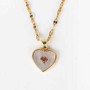 Detailed view of golden heart pendant featuring white shell inlay and pink center stone