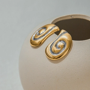 Dettaglio degli orecchini a spirale bicolore in oro e argento su vaso ceramica