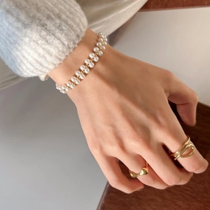 Detail view of 925 silver rings and double-row pearl bracelet on female model