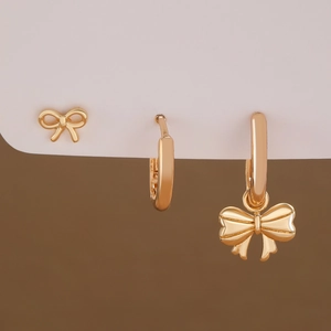 Three-piece golden bow pendant and hoop earring set with polished metallic finish