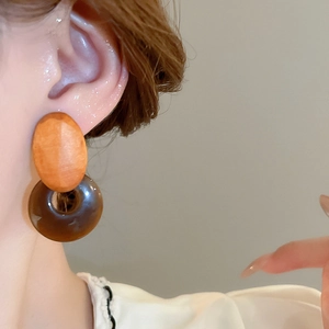 Close-up of geometric resin and wood earrings worn to show the vintage layered design