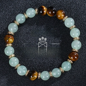 Macro detail of tiger eye and turquoise beads wealth bracelet on black texture