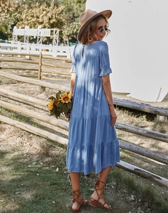 Détails d'une robe mi-longue bleue à volants étagés dans un décor de ferme en plein air
