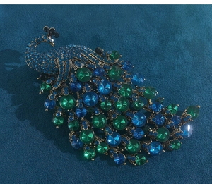 Detailed view of luxury peacock brooch with blue and green crystals on gold base