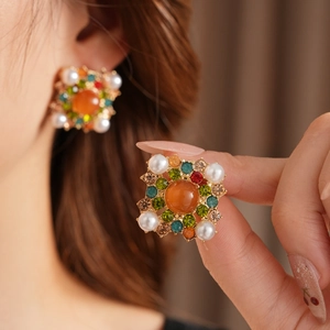 Détail de boucles d'oreilles vintage carrées avec pierres orange, strass et perles blanches