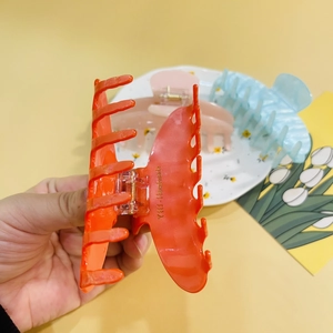 Detail showing the handmade text on a large orange acrylic hair claw clip for women